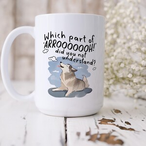 May include: A white ceramic mug featuring a graphic of a howling husky dog with the text "Which part of ARROOOOOOH! did you not understand?" printed above the illustration. The dog is depicted in shades of gray and tan against a blue sky background.