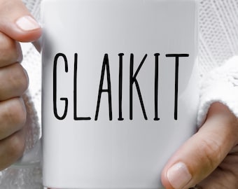 May include: A white ceramic mug featuring the word GLAIKIT printed in a simple, black, sans-serif font. The mug has a smooth, cylindrical body with a handle on the side, providing a clean and straightforward design for holding hot or cold beverages.