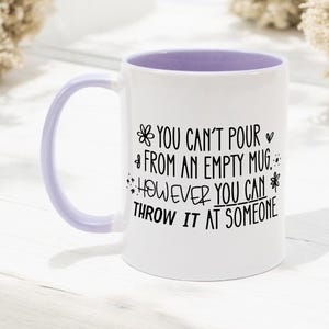 May include: White ceramic mug with a lavender interior and handle. The mug features black text that reads "YOU CAN'T POUR FROM AN EMPTY MUG. HOWEVER YOU CAN THROW IT AT SOMEONE."