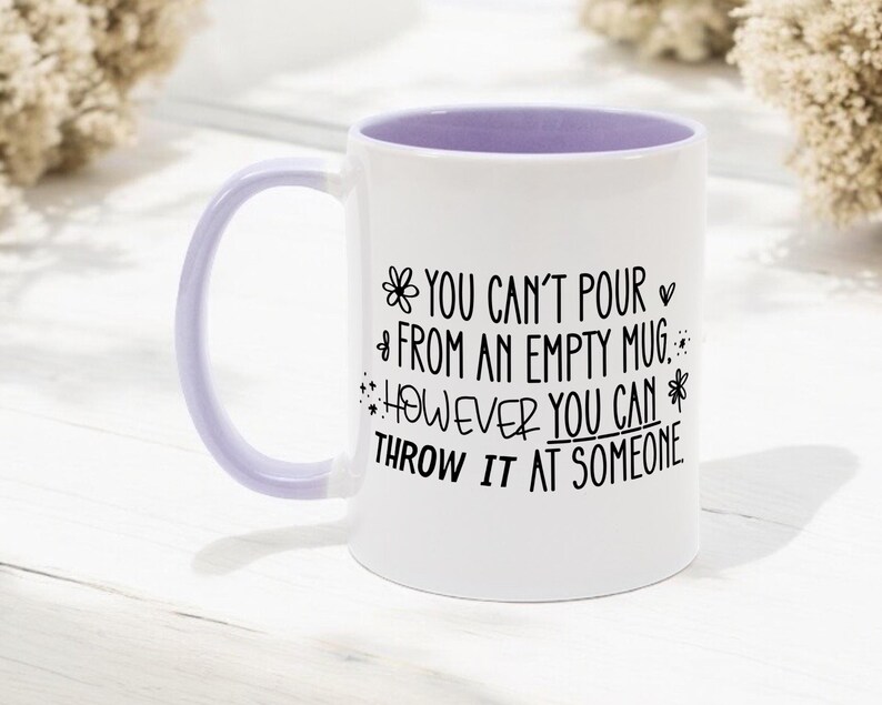May include: White ceramic mug with a lavender interior and handle. The mug features black text that reads "YOU CAN'T POUR FROM AN EMPTY MUG. HOWEVER YOU CAN THROW IT AT SOMEONE."