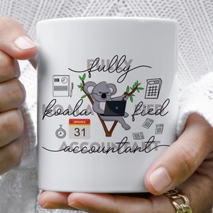 May include: White ceramic mug featuring a cartoon koala wearing glasses and using a laptop. The text "fully koala-fied accountant" is written in black cursive with a calendar and clock graphic.