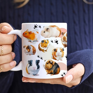 May include: White ceramic mug with a colorful design of various guinea pigs. The guinea pigs are depicted in different poses and colors, including brown, white, black, and orange. The mug has a black handle.