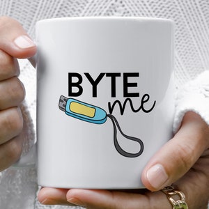 Peut inclure: Une tasse en céramique blanche avec un motif noir et blanc d'une clé USB et le texte "BYTE me".