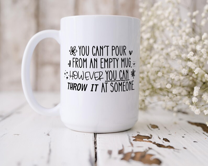 May include: White ceramic mug with a large handle. The mug features black text that reads, "YOU CAN'T POUR FROM AN EMPTY MUG. HOWEVER YOU CAN THROW IT AT SOMEONE."
