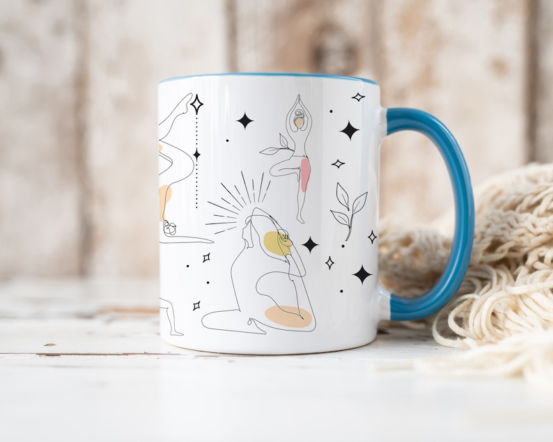 May include: White ceramic mug with a blue handle and rim. The mug features black line art illustrations of yoga poses, with yellow and pink accents. The design also includes decorative stars and leaves.