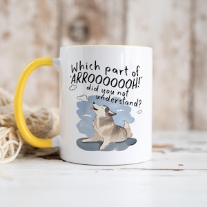 May include: A white ceramic mug with a bright yellow handle and interior. The front features a graphic of a howling husky dog on a blue patch with the black text: Which part of 'ARROOOOOOH!' did you not understand? The design includes small cloud icons.