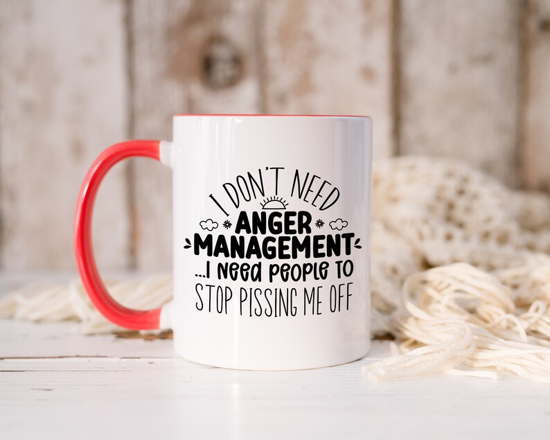 Może przedstawiać: Biały kubek ceramiczny z czerwonym rantem i uchwytem. Kubek ma czarny napis: "I don't need #ANGER* -MANAGEMENT... I need people to STOP PISSING ME OFF".