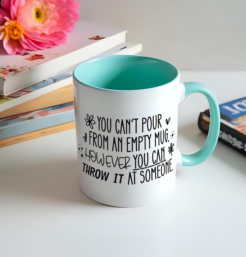 May include: White ceramic mug with a teal interior and handle. The mug features black text that reads "YOU CAN'T POUR FROM AN EMPTY MUG, HOWEVER YOU CAN THROW IT AT SOMEONE."
