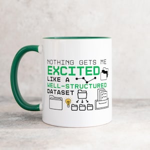 Puede incluir: Taza de cerámica blanca con borde y asa verdes. La taza tiene un gráfico negro que dice "Nada me emociona más que un conjunto de datos bien estructurado" con iconos de carpetas, archivos y una bombilla.