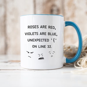 Może przedstawiać: Biały ceramiczny kubek do kawy z niebieskim rantem i uchwytem. Kubek zawiera humorystyczny napis: "Roses are red, violets are blue, unexpected '{' on line 32." Napisowi towarzyszą trzy kresk&oacute;wkowe twarze.