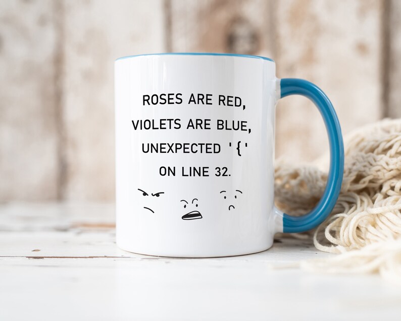 Może przedstawiać: Biały ceramiczny kubek do kawy z niebieskim rantem i uchwytem. Kubek zawiera humorystyczny napis: "Roses are red, violets are blue, unexpected '{' on line 32." Napisowi towarzyszą trzy kresk&oacute;wkowe twarze.