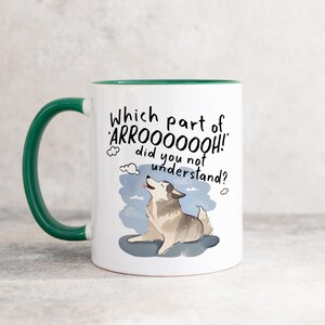 May include: A white ceramic mug with a dark green handle and interior. The front features a graphic of a howling dog with the black text: Which part of ARROOOOOOH! did you not understand? The dog is grey and white, set against a blue sky background.