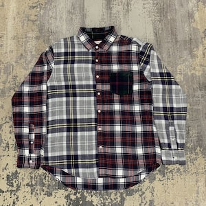 May include: A long-sleeved shirt with a patchwork plaid design. The shirt combines red, white, navy, and yellow plaid patterns. It has a button-down front, a collar, and a single chest pocket.