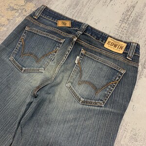 Op de afbeelding: Blauwe jeans met een vervaagde wassing. De jeans heeft twee achterzakken met decoratieve stiksels en een leren label met de merknaam "EDWIN MADE IN JAPAN".