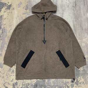 May include: A brown fleece hooded pullover with a black zip and black pocket accents. The pullover features a drawstring at the hem and a small logo on the sleeve. The material looks soft and warm.