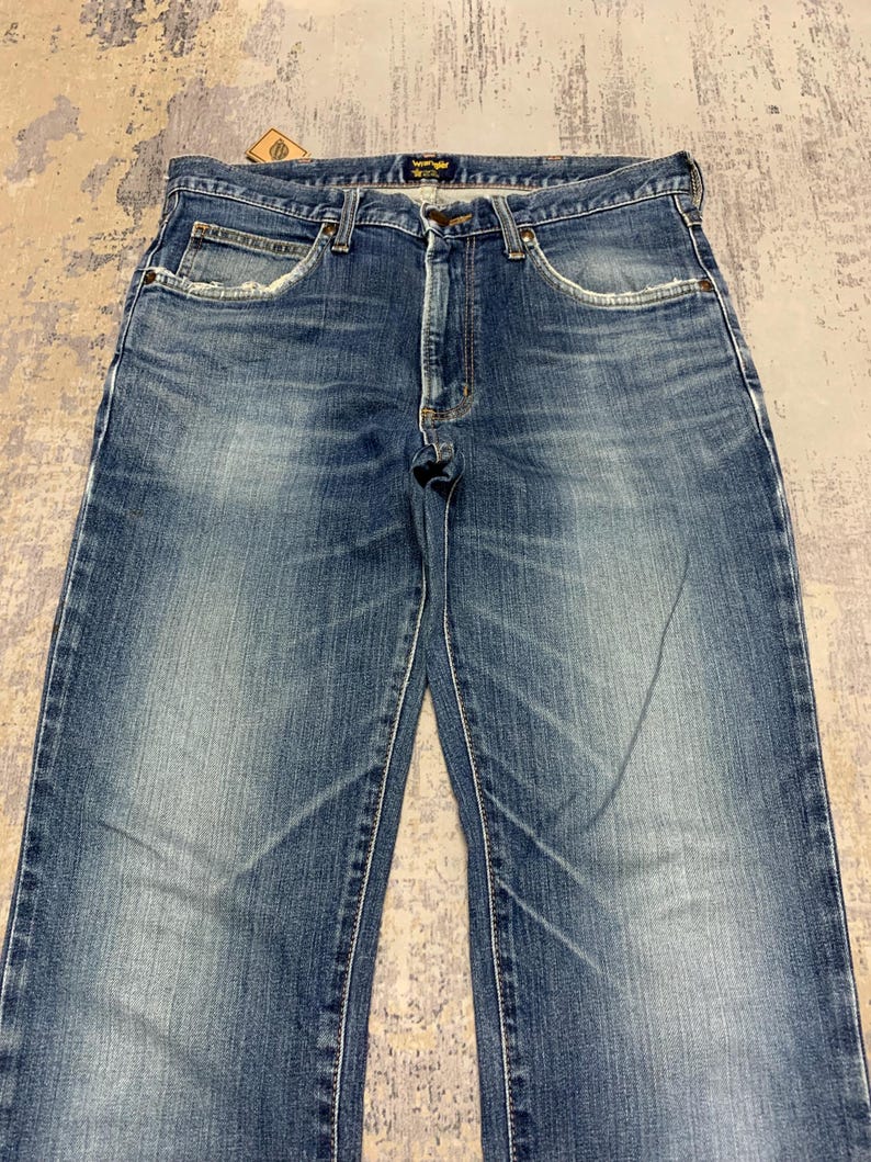 May include: Blue denim jeans with a classic five-pocket design. The jeans have a faded wash and a straight leg cut. Features include a button and zipper closure, and belt loops. The jeans are made of durable denim material.
