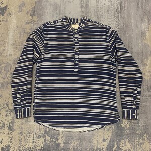 May include: A long-sleeved shirt with a mandarin collar and a horizontal striped pattern in navy blue and white. The shirt has a button-down placket and buttoned cuffs. The fabric appears to be a textured cotton or linen.