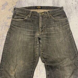 Pu&ograve; includere: Un paio di jeans Wrangler neri sbiaditi. I jeans hanno un classico design a cinque tasche, una chiusura con bottone e cerniera e un'etichetta Wrangler in vita. Il denim ha un aspetto usurato e vissuto con cuciture visibili.