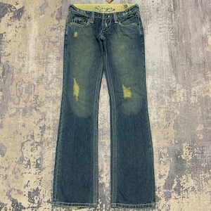 May include: Blue denim jeans featuring a low-rise waist, a button and zip fly, and distressed detailing on the thighs. The interior waistband is lined with a yellow fabric printed with the word Spiga. The jeans have a straight leg cut.