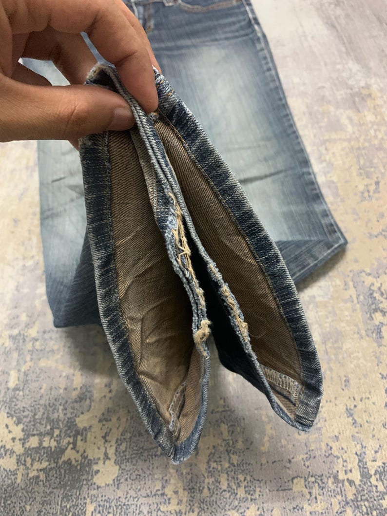 Op de afbeelding: Close-up van lichtblauwe denim jeans. De jeans is opgevouwen en onthult de binnenvoering en naden. De denim heeft een vervaagde uitstraling, met zichtbare slijtage. De stof is van een gemiddeld gewicht, geschikt voor dagelijks gebruik.
