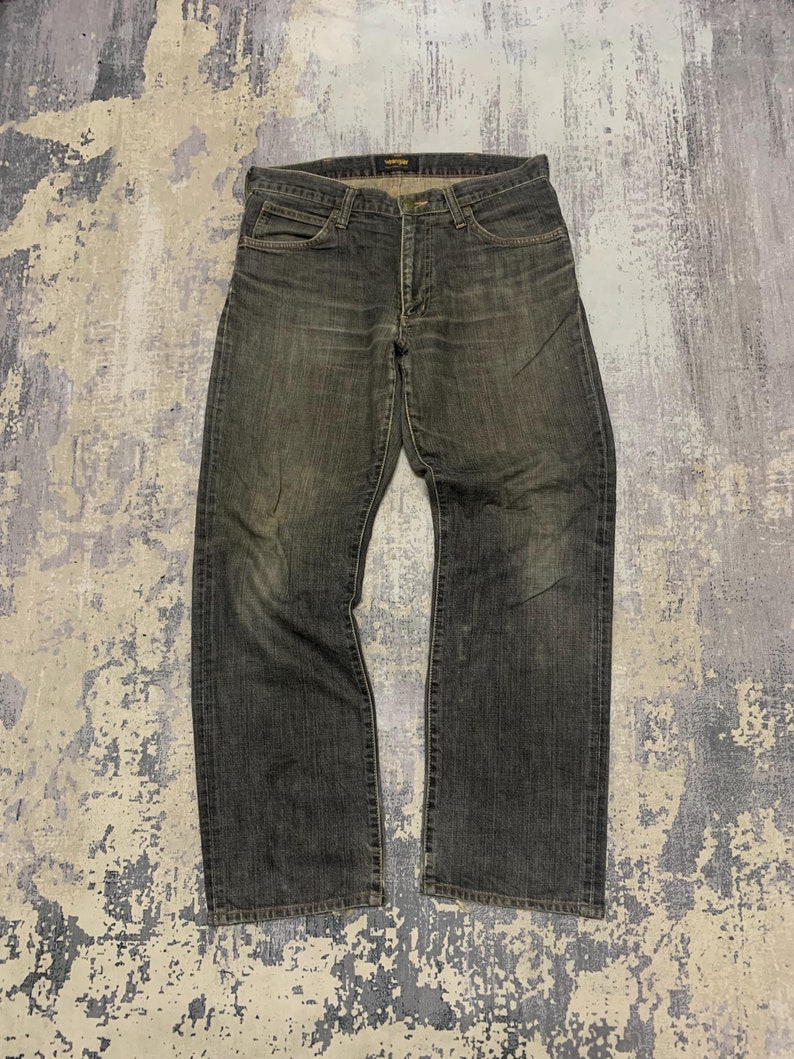 Pu&ograve; includere: Jeans in denim grigio scuro con un aspetto sbiadito. I jeans hanno un classico design a cinque tasche, una chiusura con bottone e cerniera e un taglio dritto. Il tessuto mostra segni di usura, conferendo loro un aspetto vintage.