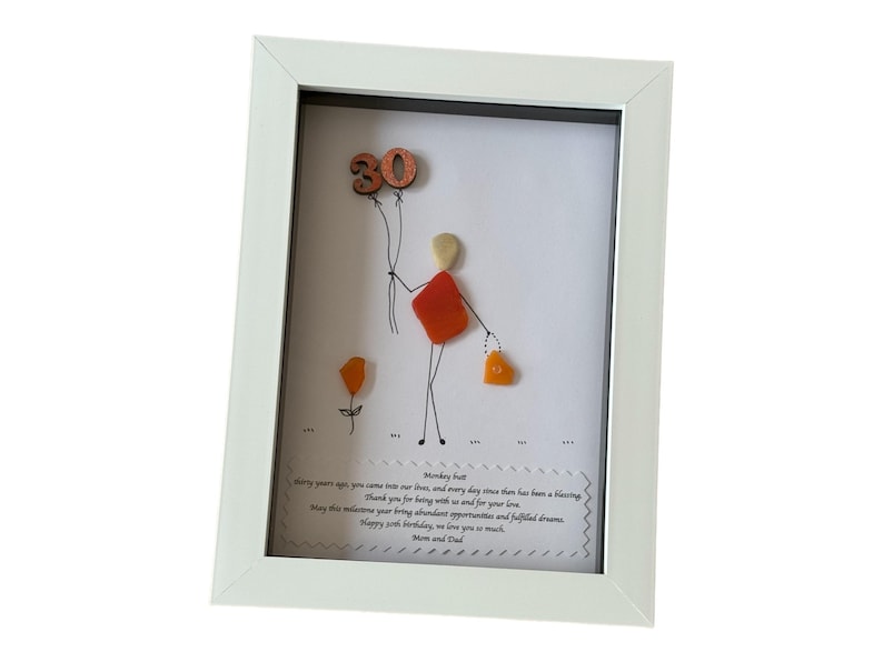 May include: A white framed picture with a hand-drawn figure made of colorful stones holding a balloon with the number 30 on it. The picture includes a message that reads "Thirty years ago you came into our love, and every day since then has been a blessing. Thank you for being with us and for your love. May this milestone bring abundance, opportunities and fulfilled dreams. Happy 30th Birthday, we love you so much. Mom and Dad."