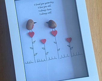 May include: A framed artwork with a white background and a handwritten message that reads "I loved you yesterday. I love you still. I always have. I always will." Two small brown birds with red hearts are perched on stems with green leaves.