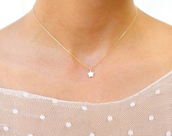 Puede incluir: Un delicado collar de cadena dorada con un pequeño colgante de estrella blanca.