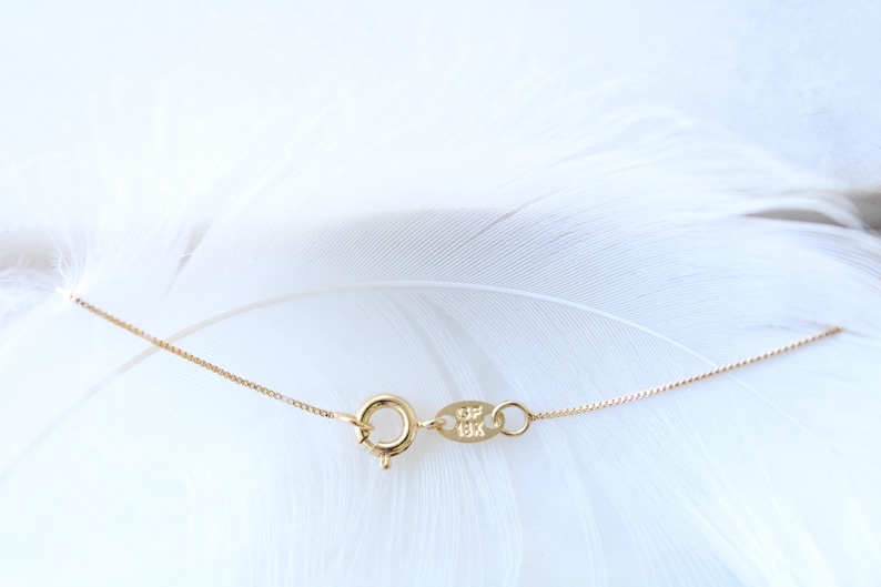 May include: A gold chain necklace with a lobster clasp and a small tag with the inscription "925" on it.