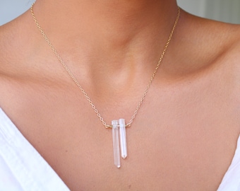 May include: A gold chain necklace with two clear quartz crystal pendants hanging from it.