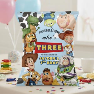 May include: A colorful party favor bag featuring characters from the animated film "Toy Story." The bag has a blue background with the text "You've got a friend who's THREE." The bag is decorated with images of Woody, Buzz Lightyear, and other characters.