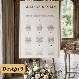 Puede incluir: Un cartel de plano de asientos de boda blanco con texto negro que muestra los nombres Adriana & Torin, una mesa principal y nueve mesas numeradas con nombres de invitados, en un caballete dorado con rosas blancas y rosadas.