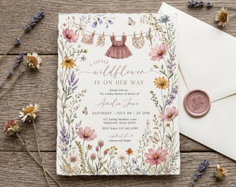 May include: A rectangular baby shower invitation card with deckled edges, featuring a watercolor wildflower border, a clothesline with baby clothing, and text reading A LITTLE wildflower IS ON HER WAY, Amelia Jane, July 08, 2PM, and address details.