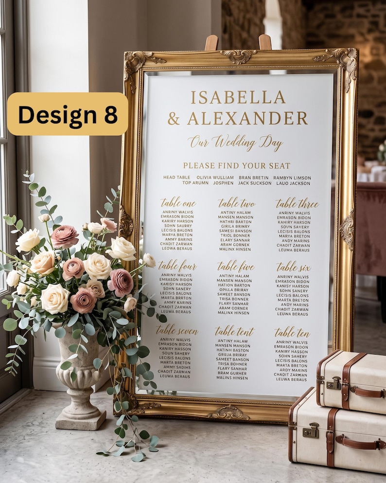 Puede incluir: Un plano de asientos de boda en un marco dorado ornamentado con fondo blanco y texto dorado que dice Isabella & Alexander Our Wedding Day. El plano enumera las mesas de la uno a la diez con nombres de invitados. Un arreglo floral est&aacute; a la izquierda.