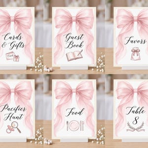 May include: A set of six rectangular event signs featuring a large, soft pink watercolor bow at the top. Each sign displays black cursive text and a corresponding icon, including Cards & Gifts, Guest Book, Favors, Pacifier Hunt, Food, and Table 8.