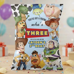 May include: A colorful chip bag featuring characters from the Toy Story movie. The bag has a blue background with the text "YOU'VE GOT A FRIEND who's THREE" and "JAYDEN'S 3RD BDAY". The bag is decorated with cartoon characters.