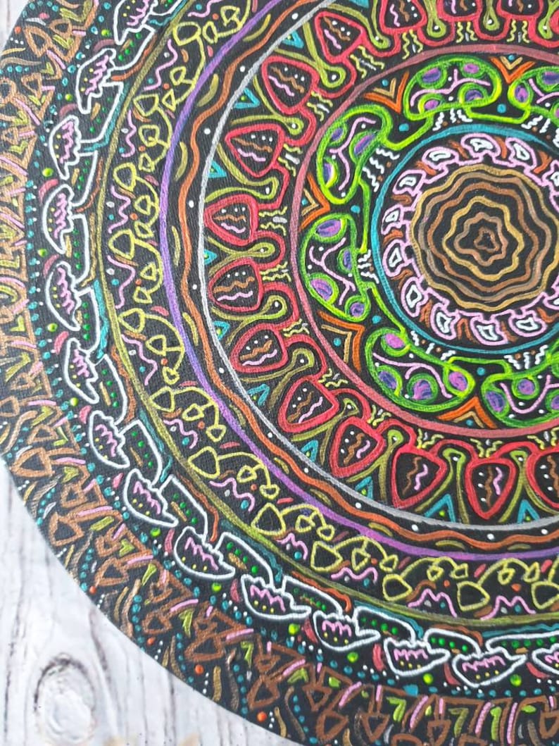 Pode incluir: Um design circular de mandala pintado em uma tela preta. O mandala apresenta uma variedade de cores, incluindo vermelho, verde, amarelo, azul e roxo. O design &eacute; intrincado e detalhado, com uma variedade de formas geom&eacute;tricas e padr&otilde;es.