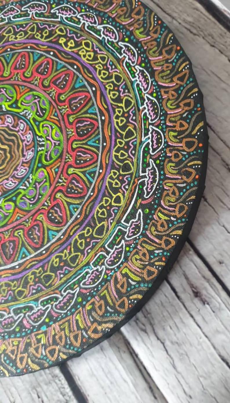 Pode incluir: Uma tela circular de madeira com um design de mandala colorido pintado sobre ela. O mandala apresenta uma variedade de formas geom&eacute;tricas e padr&otilde;es em tons de rosa, amarelo, verde, azul e laranja. O design &eacute; intrincado e detalhado, e as cores s&atilde;o vibrantes e chamativas.