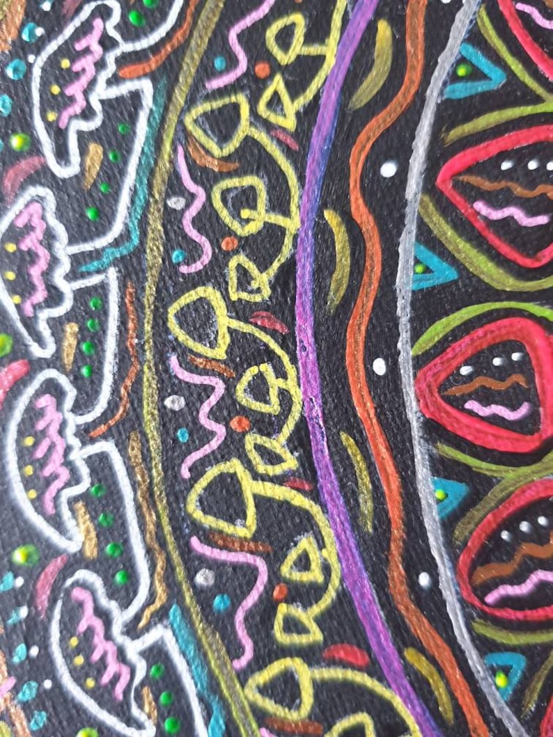 Pode incluir: Um close-up de um desenho circular de mandala pintado em uma superf&iacute;cie preta. O desenho apresenta uma variedade de cores, incluindo rosa, amarelo, verde, azul, vermelho e branco. O desenho &eacute; intrincado e detalhado, com uma variedade de formas e padr&otilde;es.