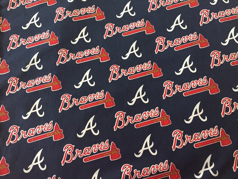 May include: Navy blue fabric with a repeating pattern of the Atlanta Braves logo. The logo includes the word "Braves" in red script and a red tomahawk, along with a white "A" symbol.