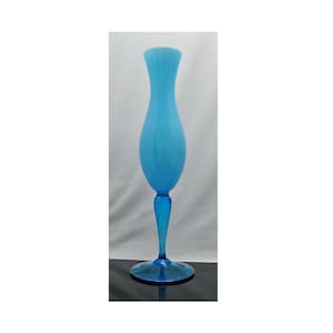 May include: A tall, elegant, light blue glass vase. The vase has a slender, elongated body that flares slightly at the top. It sits on a round base and has a stem. The vase is approximately 12 inches tall.
