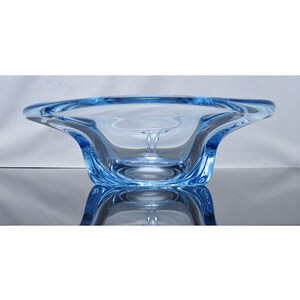 May include: A light blue glass bowl with a unique, wavy design. The bowl is made of clear glass with a light blue tint.