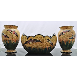 May include: A set of three ceramic vases with a yellow, green and brown colour scheme. The vases feature a stylised design of birds in flight.