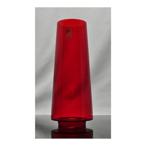 Könnte beinhalten: Eine hohe, rote Glasvase mit ausgestelltem Rand und rundem Fuß. Die Vase hat eine zylindrische Form und eine glatte, glänzende Oberfläche. Auf der Seite befindet sich ein kleiner Aufkleber. Die Vase dient wahrscheinlich dekorativen Zwecken.
