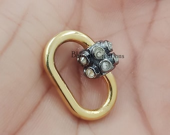 May include: A gold oval-shaped connector with a cluster of small white diamonds set in black metal. The connector is a jewelry finding.
