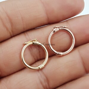 Può includere: Due piccoli orecchini a cerchio rotondi. Uno è color oro, l'altro è oro rosa. Ogni orecchino ha una chiusura a cerniera per un uso sicuro. Gli orecchini sono esposti su uno sfondo neutro.