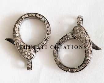 Puede incluir: Dos cierres de joyería plateados, cada uno con un diseño circular y un cierre de bisagra. Los cierres están incrustados con pequeñas piedras brillantes. El texto "BHUPATI CREATIONS" es visible en la imagen.