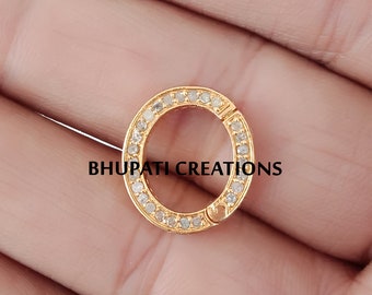 May include: A gold-colored, circular jewelry clasp with a ring of small, clear stones. The clasp is open, revealing the locking mechanism. The text "BHUPATI CREATIONS" is printed in black across the bottom of the image.