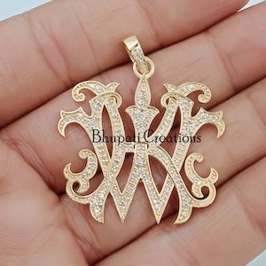 May include: Gold pendant featuring a large, ornate, double 'W' design, fully encrusted with small, clear gemstones. The pendant is on a hand, with the text "Bhupati Creations" visible below the pendant.
