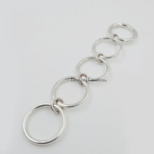 May include: A silver chain made of five interlocking rings.